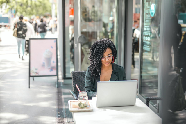 A woman works outside on her laptop