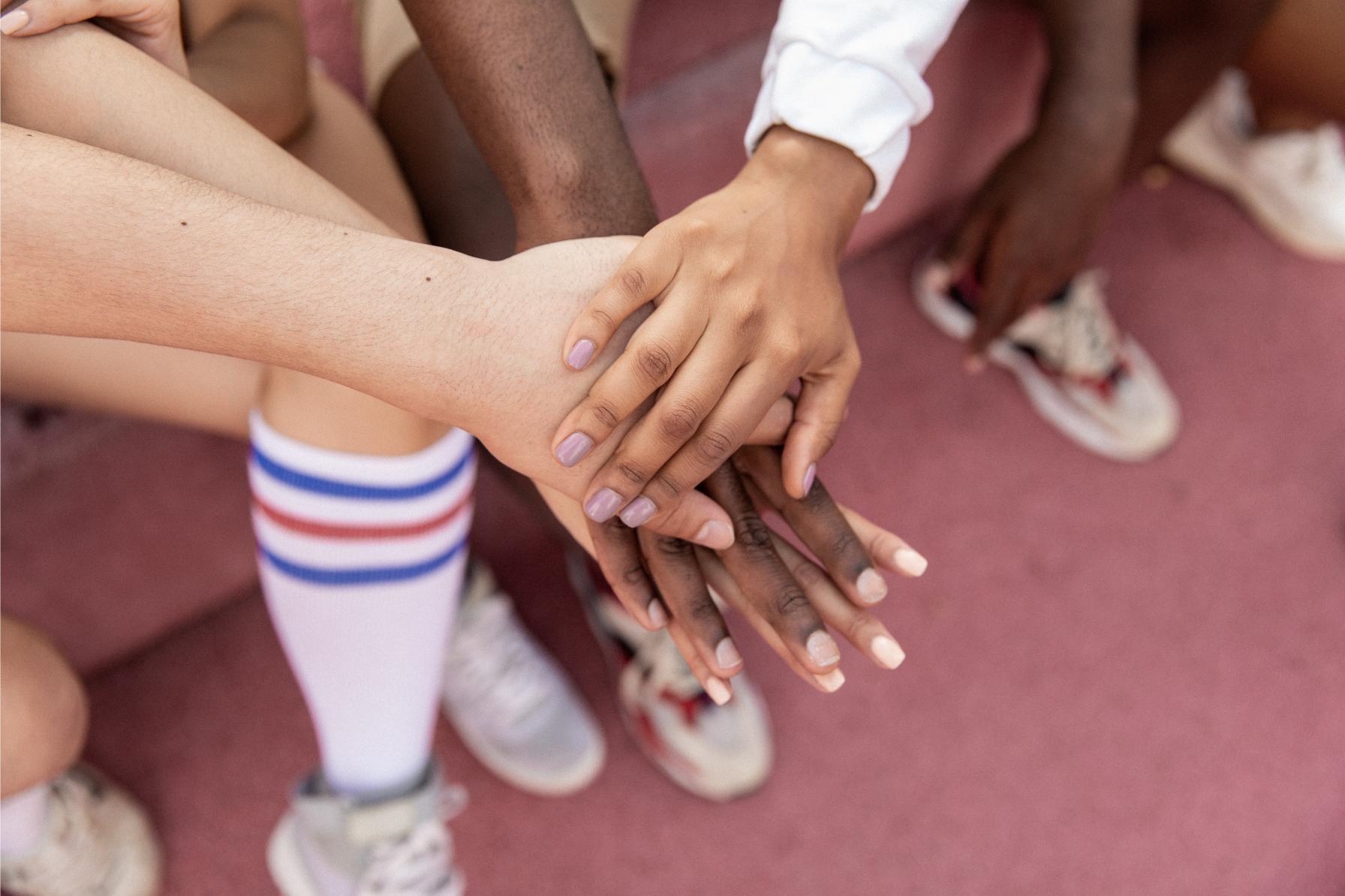Many hands join together, representing fundraising as a team effort.