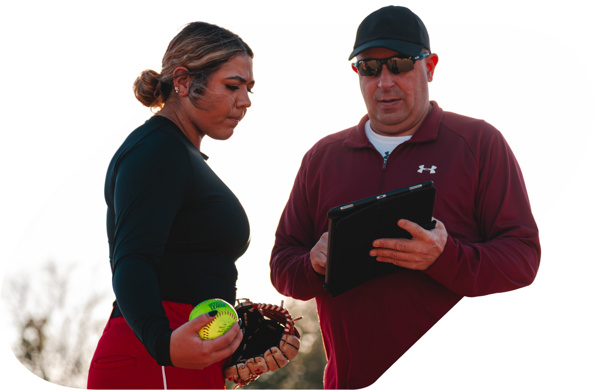 Coach pointing to an ipad screen with girl softball player