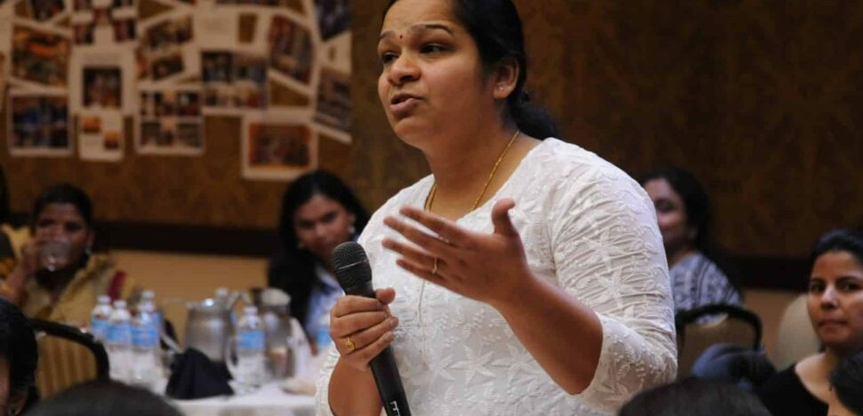 Indian mother standing with a microphone at at a parent teacher meeting